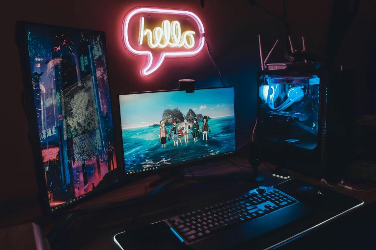 A sleek gaming setup with neon 'hello' sign, dual monitors, and illuminated PC for a futuristic vibe.